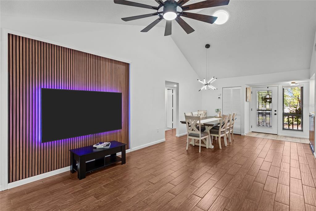 A living and dining area features wood-slat wall paneling, a mounted television, and tile flooring — 1636 BROOKHOUSE DRIVE UNIT 230, SARASOTA, FL
