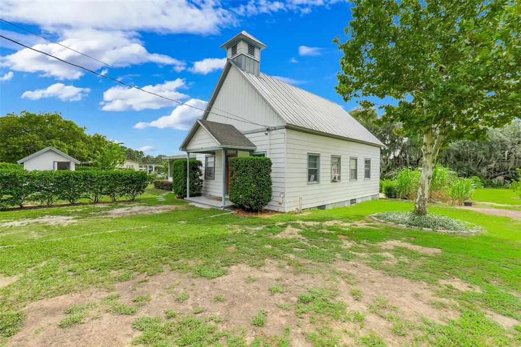 A white, one-story building with a metal roof and a small bell tower sits outdoors — 13234 SOUTH CAROLINA AVENUE, ASTATULA, FL