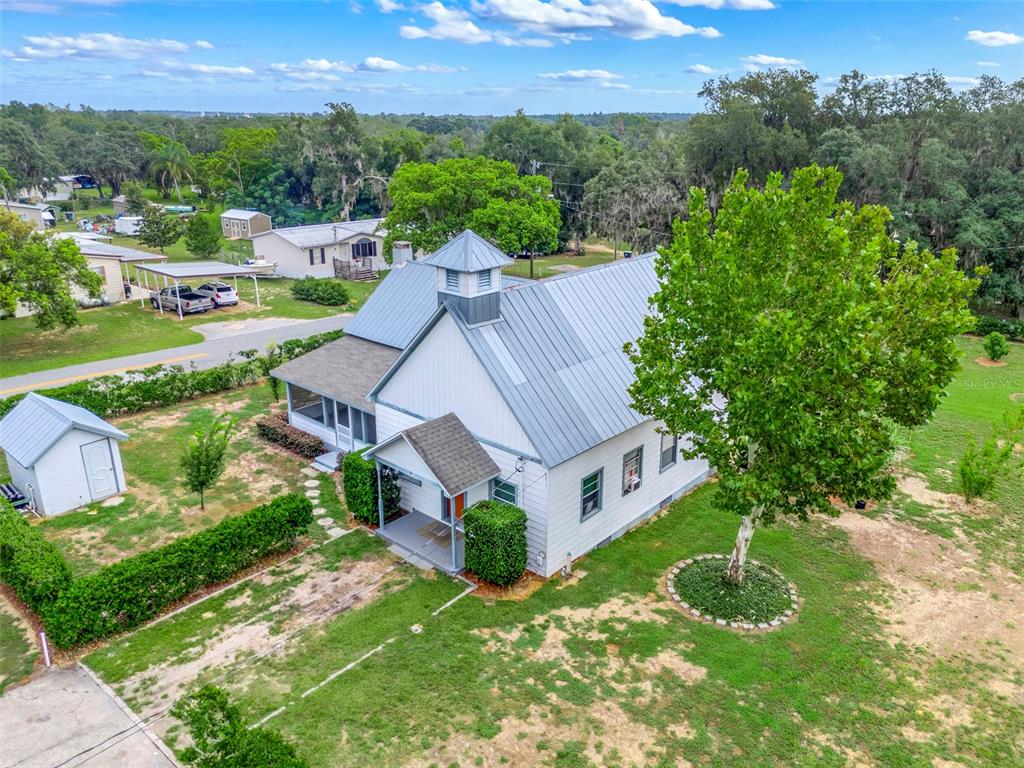 An aerial view shows a white church-style building with a metal roof and a cupola — 13234 SOUTH CAROLINA AVENUE, ASTATULA, FL