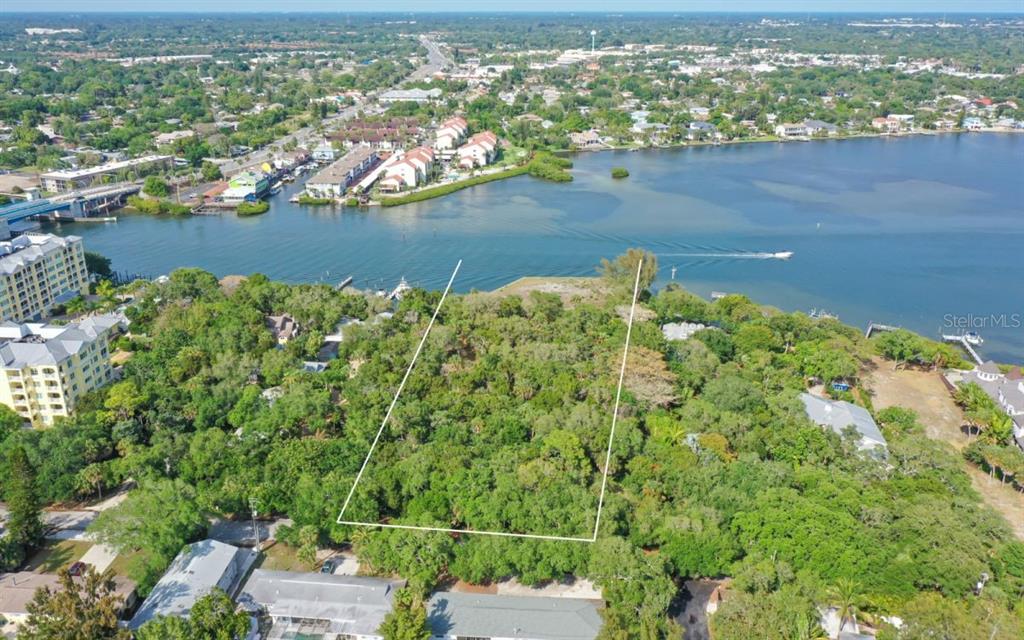 An aerial view shows a wooded waterfront lot outlined in white near a bridge — 6559 PEACOCK ROAD, SARASOTA, FL