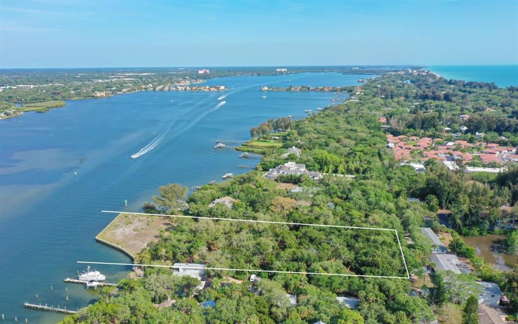 An aerial view shows a waterfront lot outlined in white amidst dense trees and vegetation — 6559 PEACOCK ROAD, SARASOTA, FL