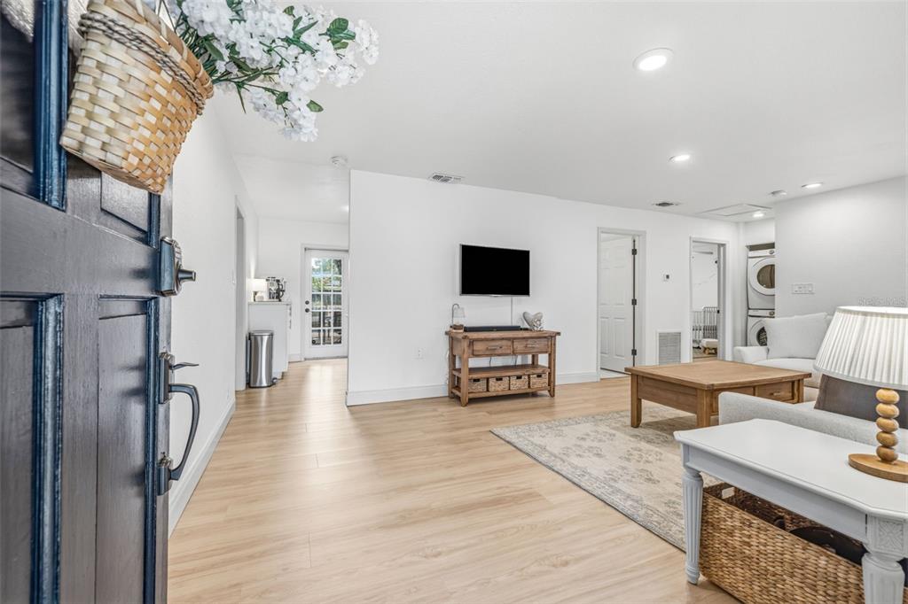 A living room features light wood flooring, white walls, a television, and a wooden coffee table — 3913 W WALLACE AVENUE, TAMPA, FL