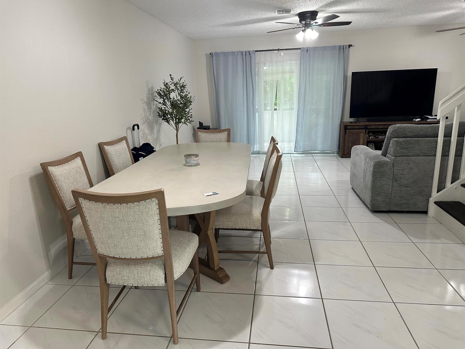 A dining area with a light-colored table and chairs sits on white tiled flooring — 1420 SW 47TH Avenue, Deerfield Beach FL 33442, DEERFIELD BEACH, FL
