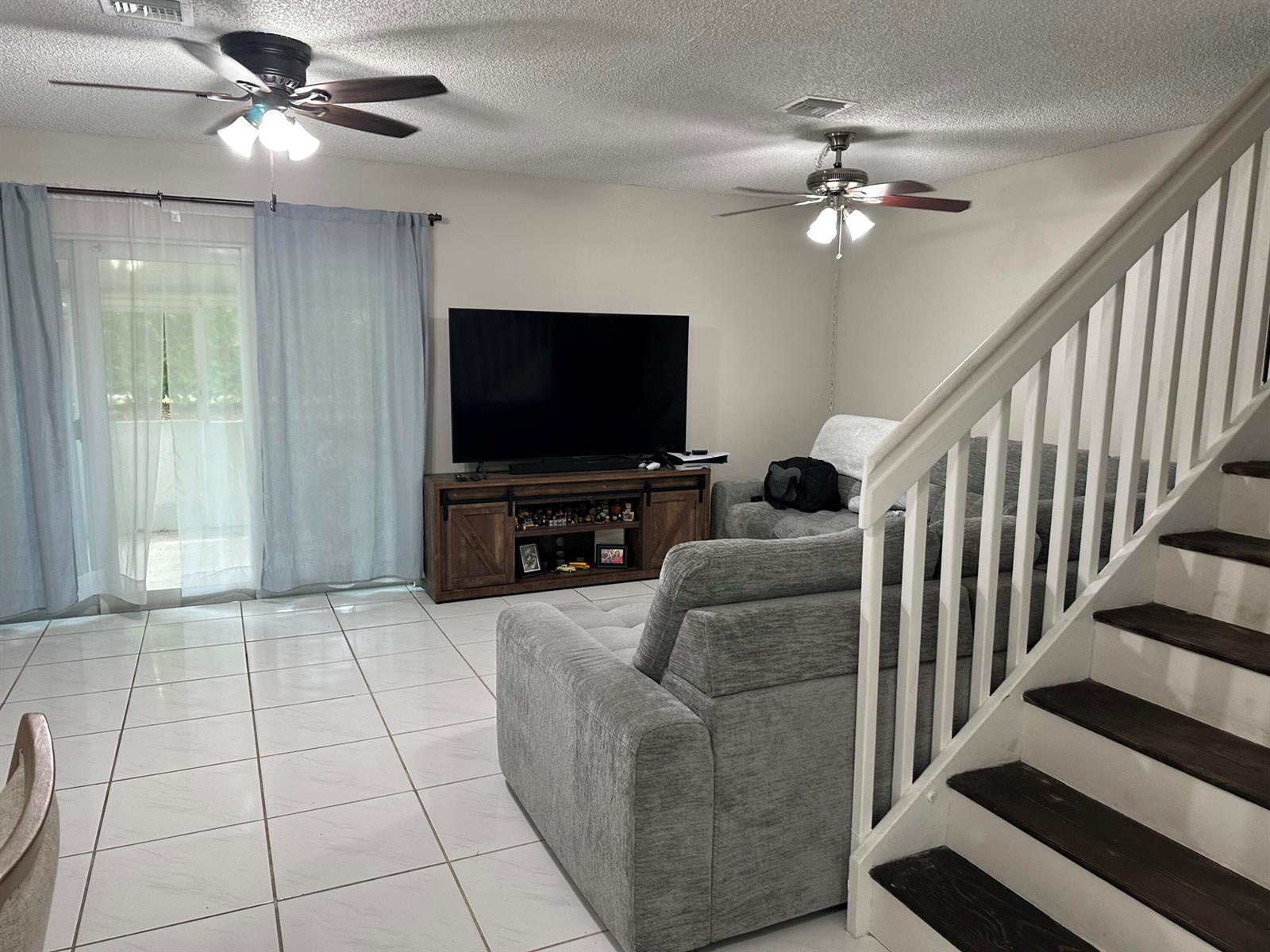 A living room features a grey sectional sofa, a TV console, and a staircase — 1420 SW 47TH Avenue, Deerfield Beach FL 33442, DEERFIELD BEACH, FL