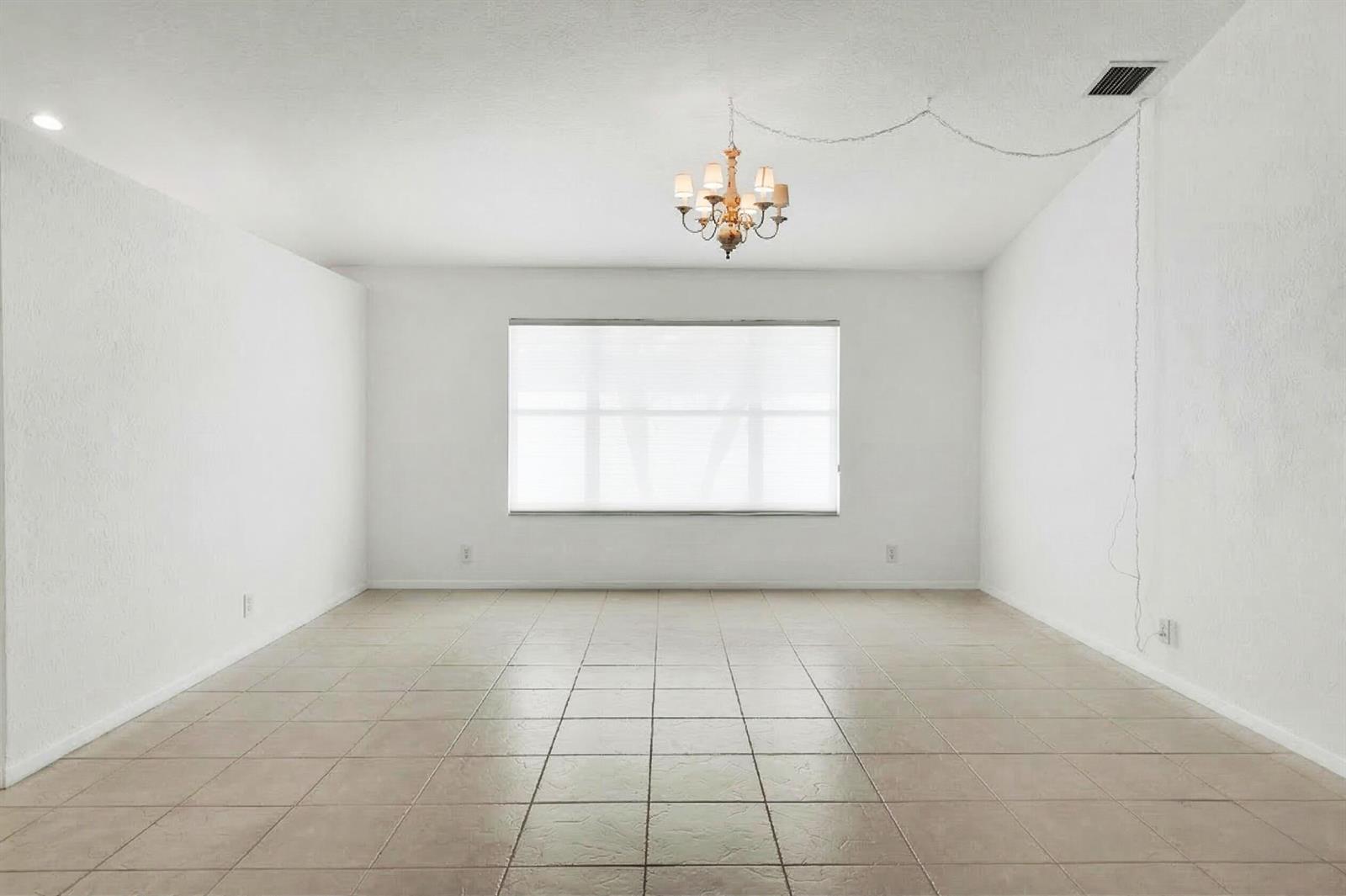 An empty room with white walls, tile flooring, a chandelier, and a large window — 10382 Utopia Circle E, Boynton Beach FL 33437, BOYNTON BEACH, FL