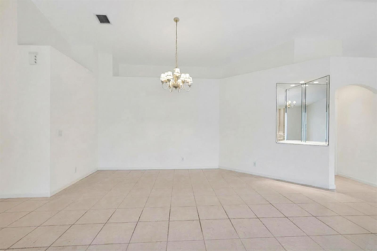 An empty dining room features white walls, tile flooring, and a central chandelier — 10382 Utopia Circle E, Boynton Beach FL 33437, BOYNTON BEACH, FL