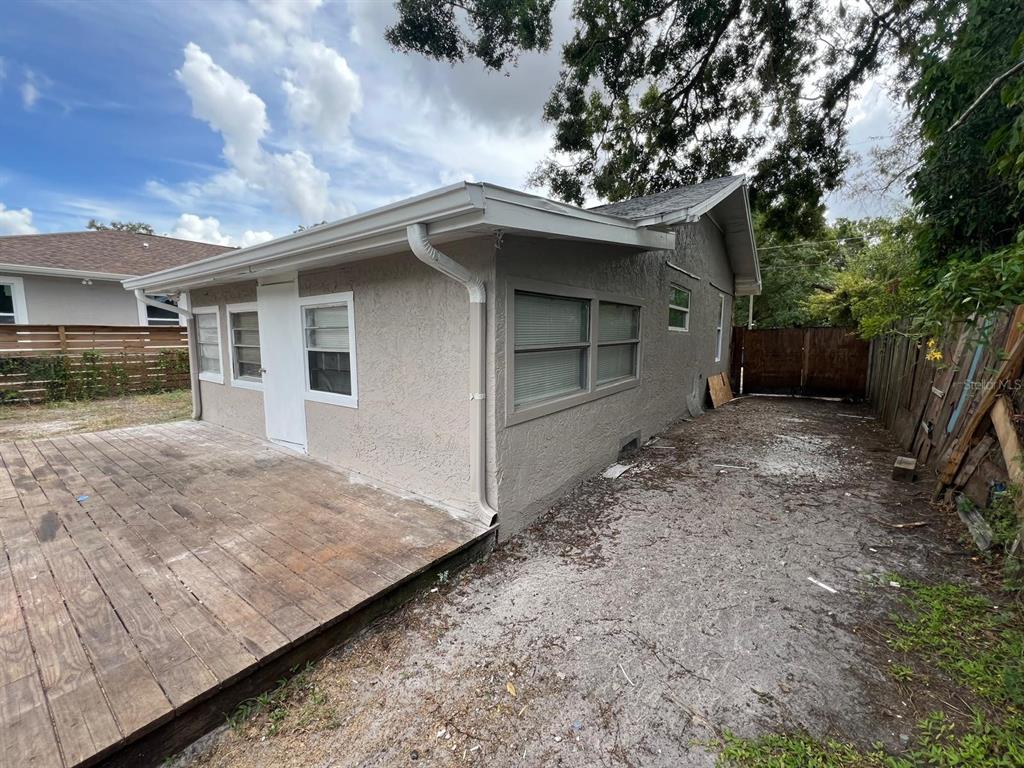 The exterior of a house features a wooden deck, stucco walls, and a white door — 1708 E NOME STREET, TAMPA, FL