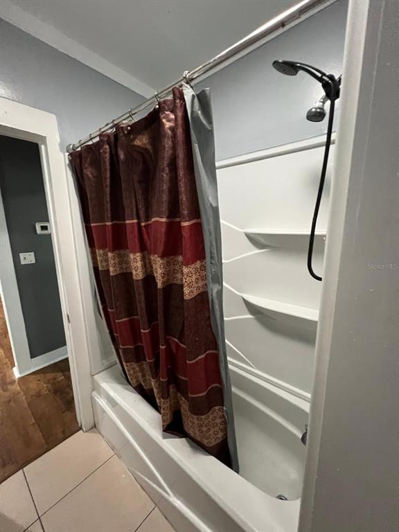 A bathroom features a white tub and shower surround with a patterned shower curtain — 1708 E NOME STREET, TAMPA, FL