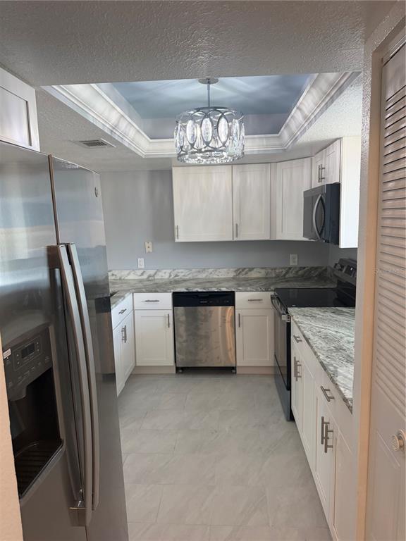 A kitchen features white cabinets, stainless steel appliances, and granite countertops under a tray ceiling — 2735 MAGDALINA DRIVE UNIT 2, PUNTA GORDA, FL
