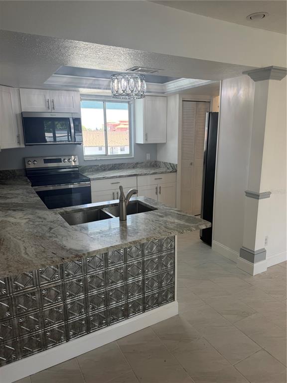 A kitchen features white cabinets, granite countertops, a metal-tiled island, and stainless steel appliances — 2735 MAGDALINA DRIVE UNIT 2, PUNTA GORDA, FL