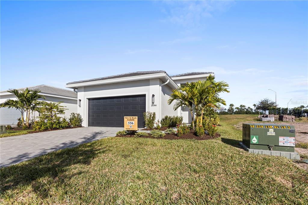A single-story house with a gray exterior, a dark garage door, and a paved driveway — 18366 ROCKPORT PLACE, LAKEWOOD RANCH, FL