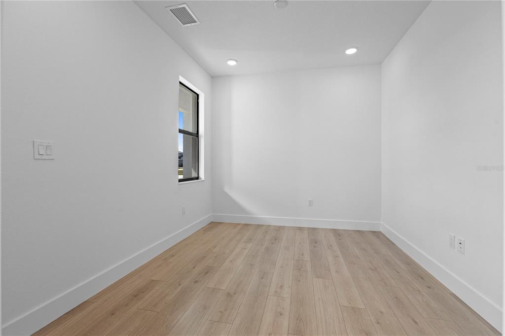An empty room with white walls, light wood-look flooring, a window, and recessed lighting — 18366 ROCKPORT PLACE, LAKEWOOD RANCH, FL