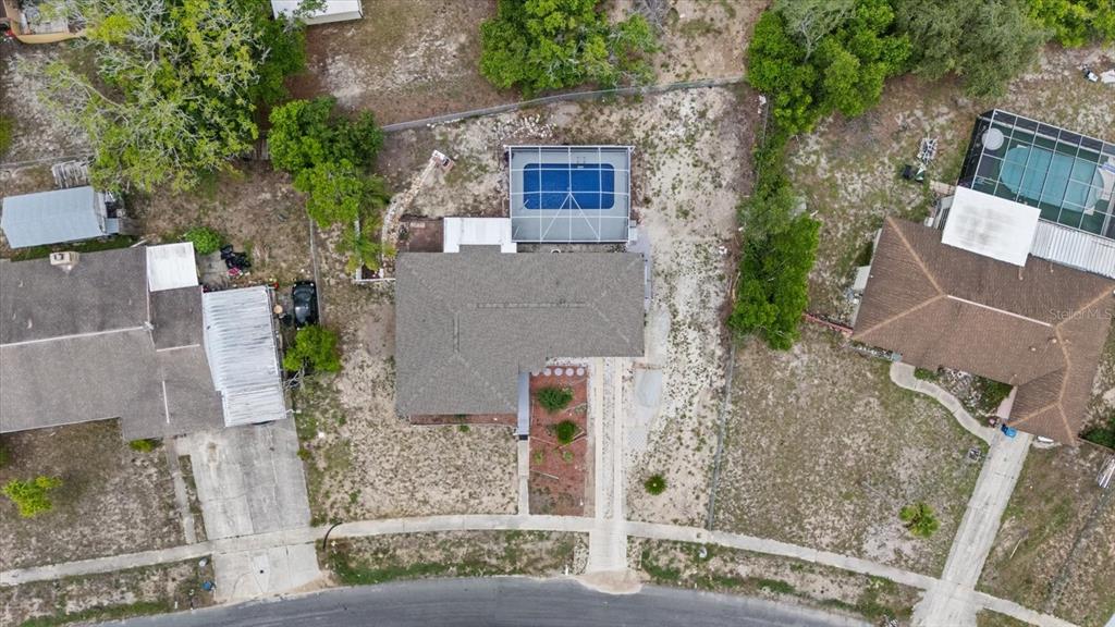 An aerial view shows a house with a pool enclosure and a large backyard — 6495 FAIRLAWN STREET, SPRING HILL, FL