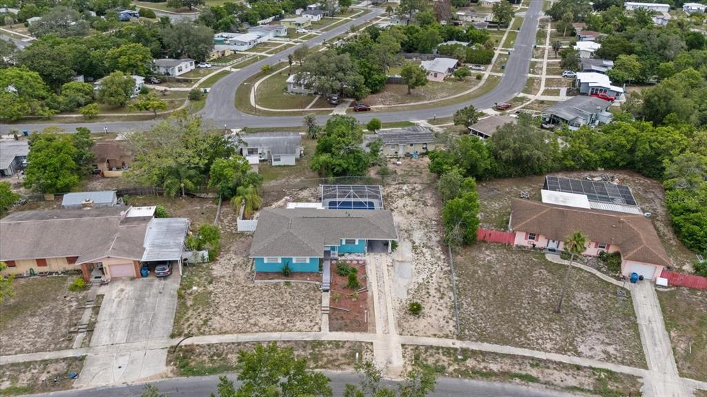 An aerial view shows three suburban houses with driveways, lawns, and a backyard swimming pool — 6495 FAIRLAWN STREET, SPRING HILL, FL