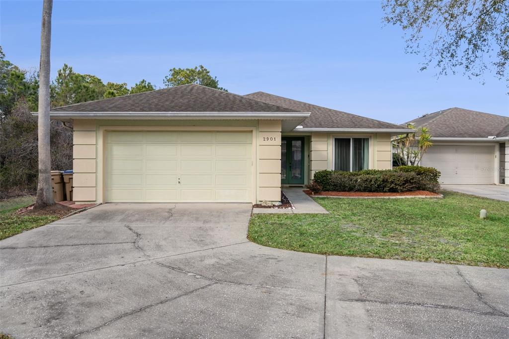 A single-story house with a beige stucco exterior, a two-car garage, and a shingled roof — 2901 SUNSET VISTA COURT, KISSIMMEE, FL