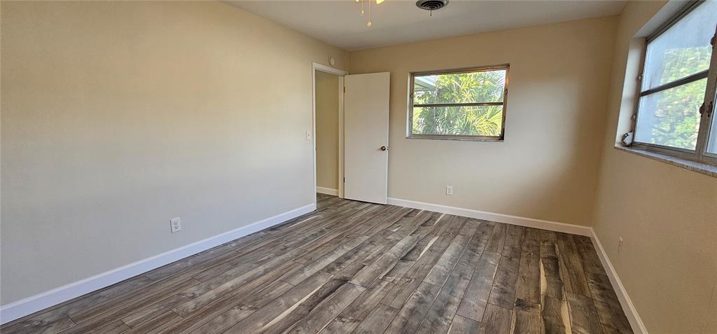 An empty bedroom features light-colored walls, wood-look tile flooring, and two windows — 1329 FAIRFIELD DRIVE, CLEARWATER, FL