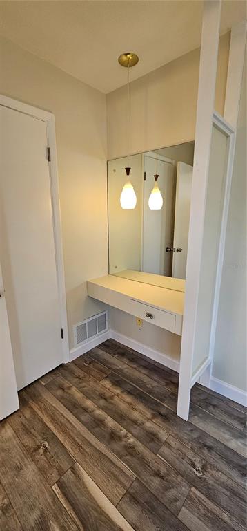 A built-in vanity with a mirror, pendant lighting, and a drawer sits on wood-look flooring — 1329 FAIRFIELD DRIVE, CLEARWATER, FL