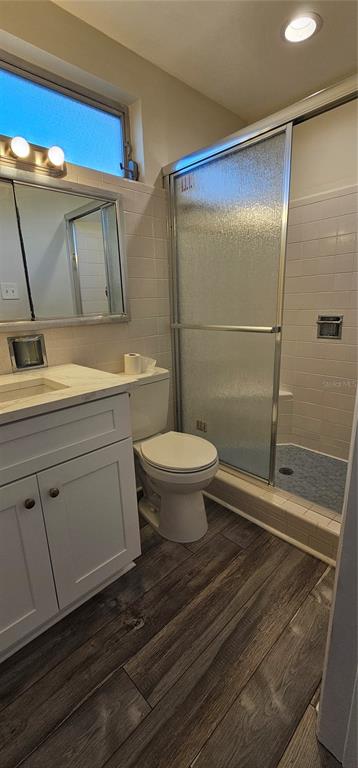 A bathroom features a white vanity, a toilet, and a glass-enclosed shower with tiled walls — 1329 FAIRFIELD DRIVE, CLEARWATER, FL
