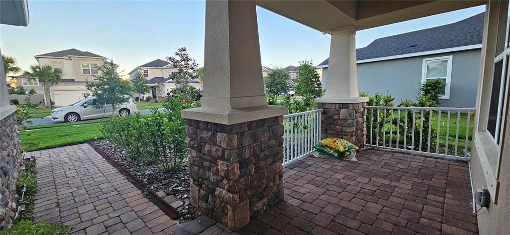 A covered front porch features stone-based columns, a paver floor, and a white railing — 13539 STANSIL AVENUE, ODESSA, FL