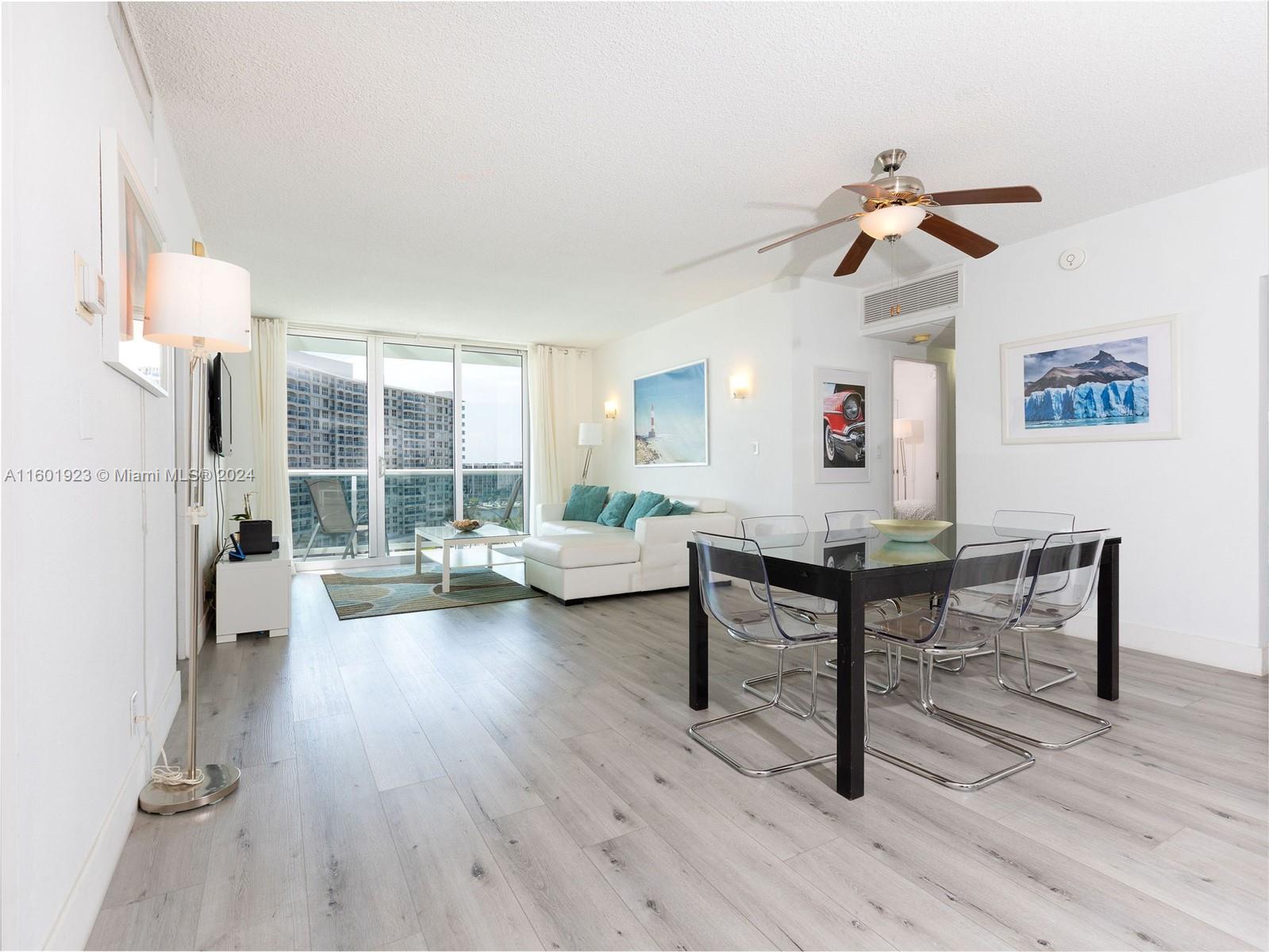 A living and dining area with light wood floors, white walls, and a balcony view — 3901 S Ocean Dr # 10P, Hollywood FL 33019, HOLLYWOOD, FL