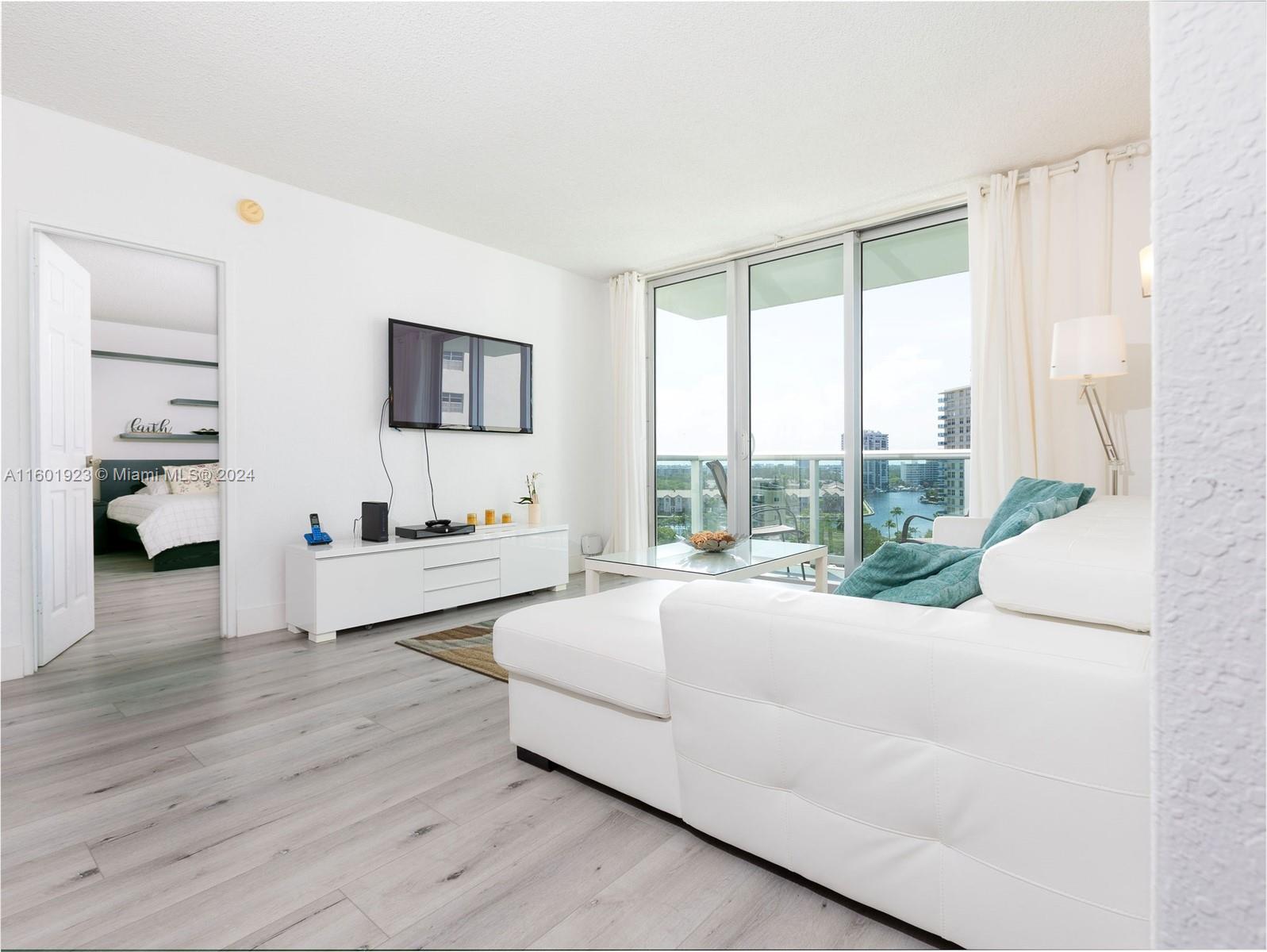 A living room features a white sectional sofa, media console, and a balcony with water views — 3901 S Ocean Dr # 10P, Hollywood FL 33019, HOLLYWOOD, FL