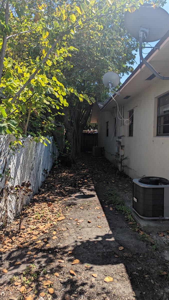 A narrow side yard features a dirt path, a chain-link fence, and an air conditioner — 1944 Taft Street, Hollywood FL 33020, HOLLYWOOD, FL