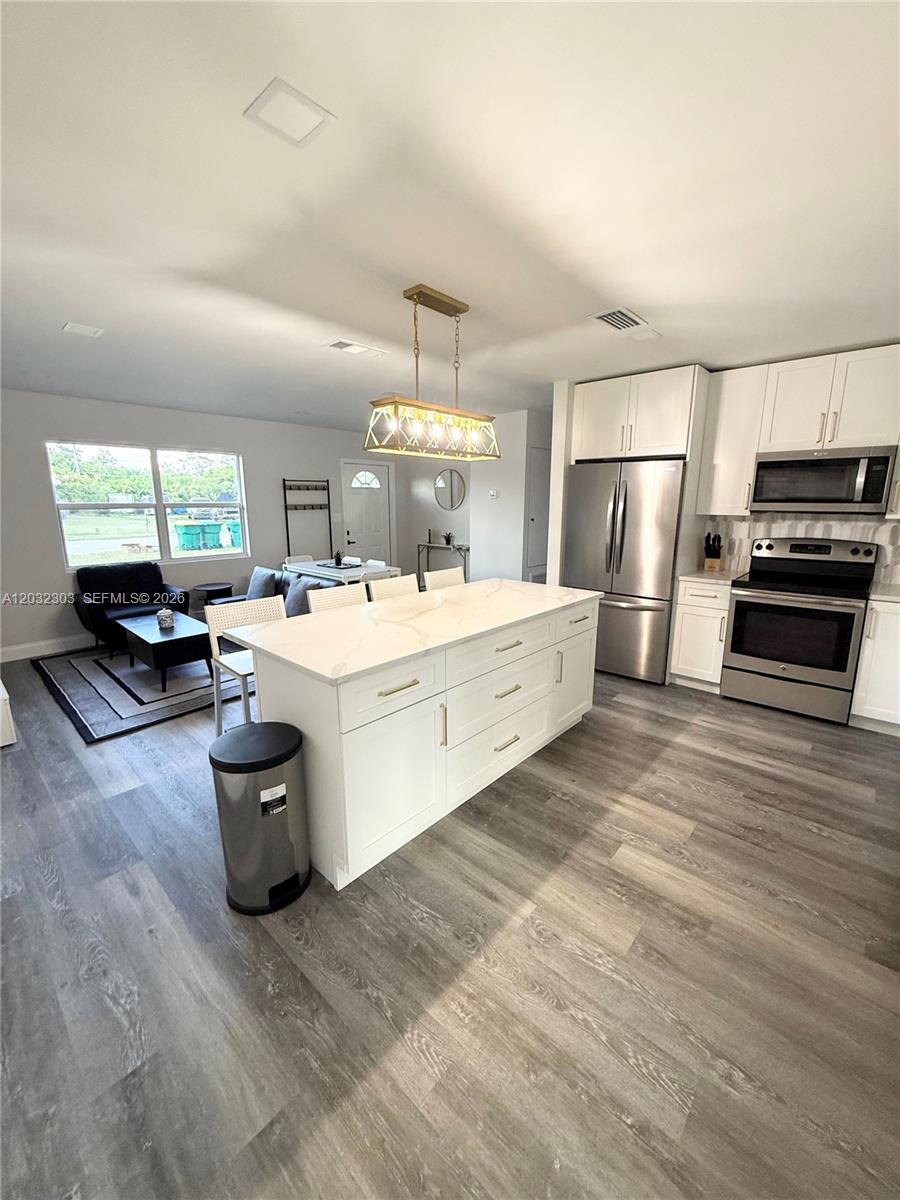 A modern kitchen features a white island, stainless steel appliances, and light wood-look flooring — 801 Broadhag Dr, Punta Gorda FL 33950, PUNTA GORDA, FL