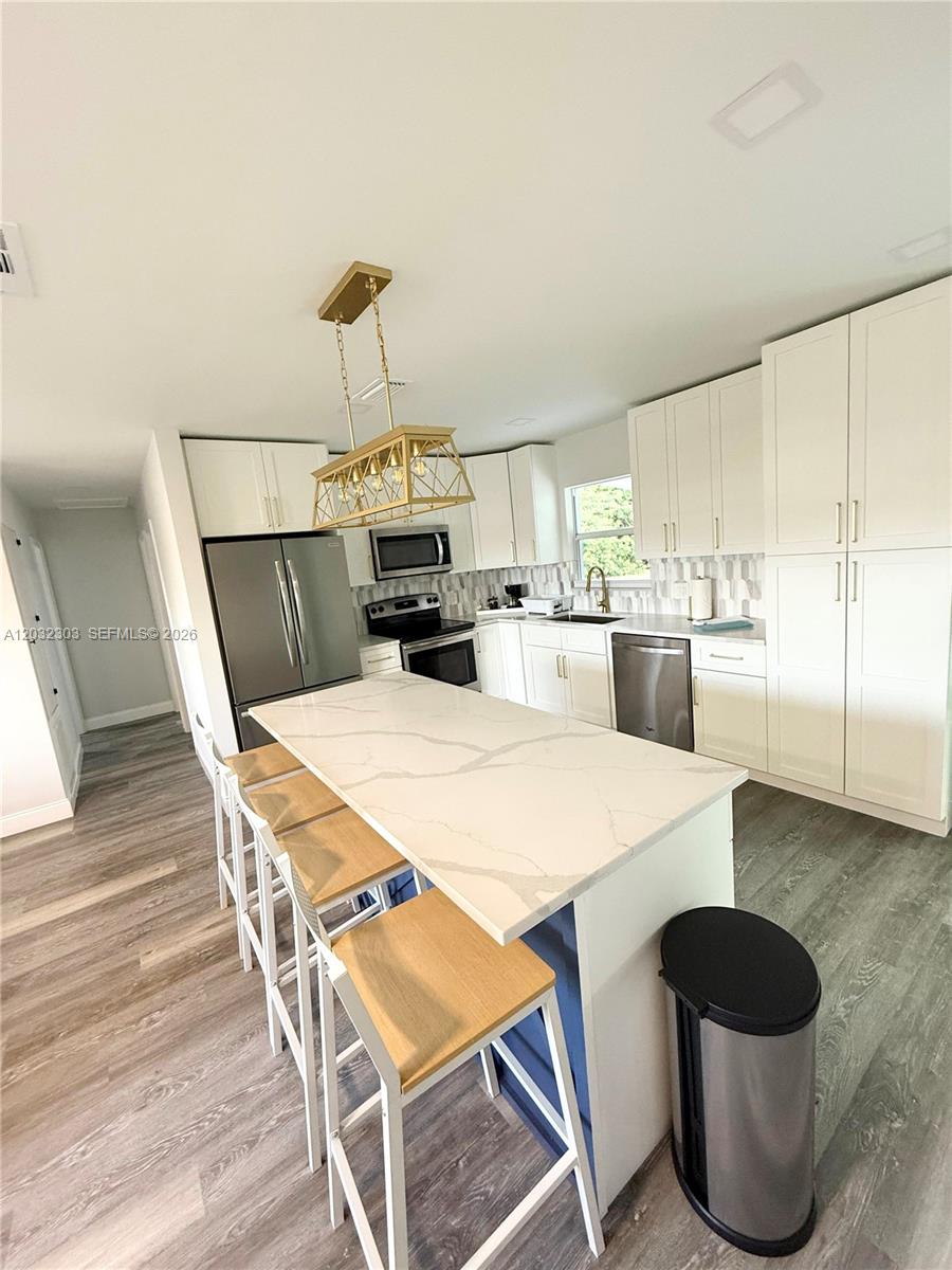 A modern kitchen features white cabinetry, a marble-topped island, and stainless steel appliances — 801 Broadhag Dr, Punta Gorda FL 33950, PUNTA GORDA, FL