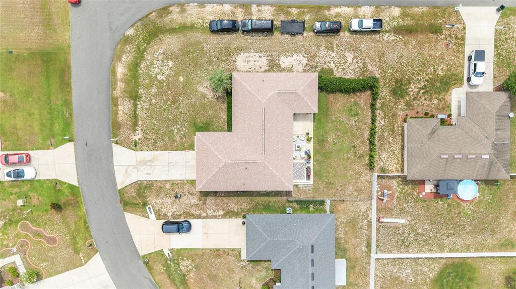 An aerial view shows a suburban house with a brown roof and a backyard patio — 10057 SE 125TH STREET, BELLEVIEW, FL