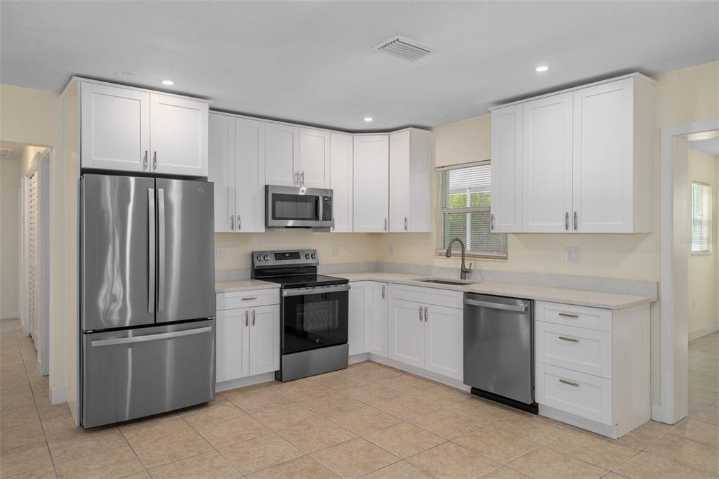 A kitchen with white cabinets, stainless steel appliances, and light-colored tile flooring — 4808 W EUCLID AVENUE, TAMPA, FL