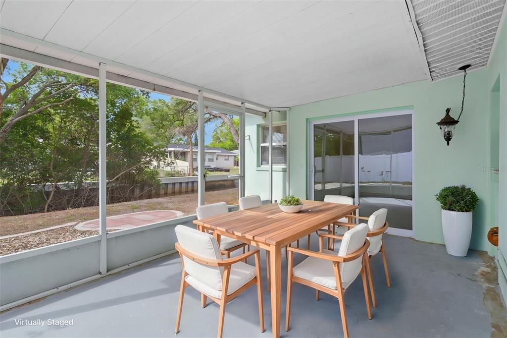 A screened-in patio features a wooden dining set and views of a canal — 4808 W EUCLID AVENUE, TAMPA, FL