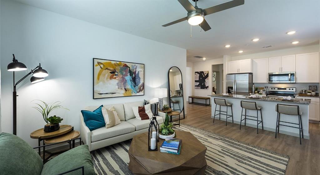 A modern open-concept living room and kitchen featuring a sofa, coffee table, and breakfast bar — 4980 RED MAPLE LANE UNIT B1, WILDWOOD, FL