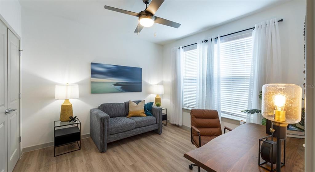 A home office features a gray sofa, a wooden desk, and a ceiling fan — 4980 RED MAPLE LANE UNIT B1, WILDWOOD, FL