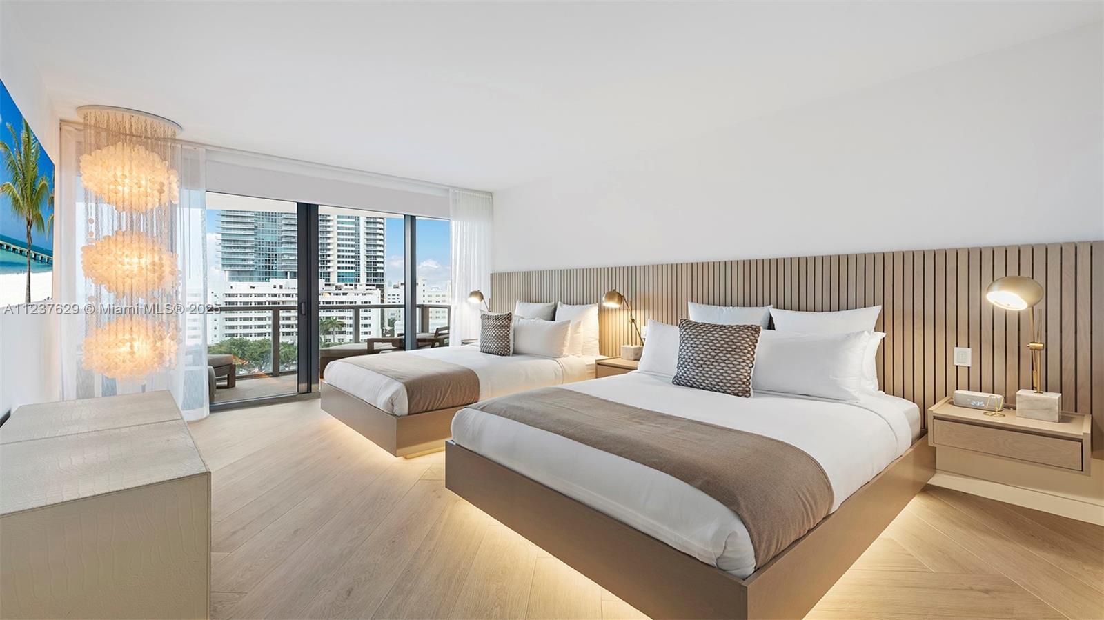 A modern bedroom features two beds, wood-slat wall paneling, and a balcony with city views — 2201 Collins Ave # 804, Miami Beach FL 33139, MIAMI BEACH, FL