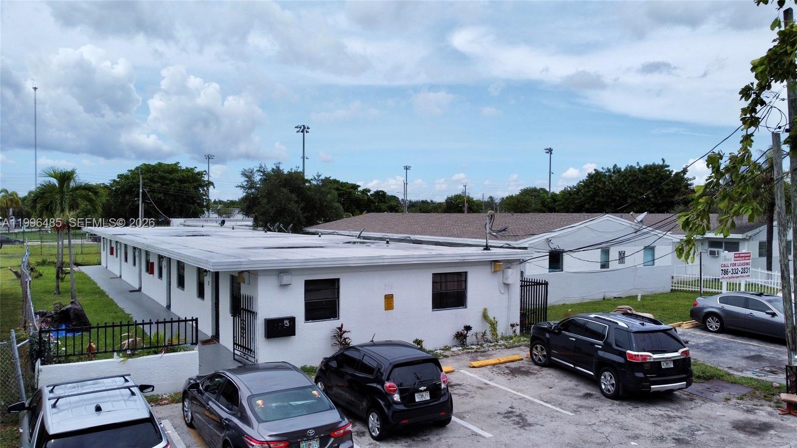 An exterior view of a single-story white apartment building with a parking lot — 715 NW 7th Ave # 4, Hallandale Beach FL 33009, HALLANDALE BEACH, FL