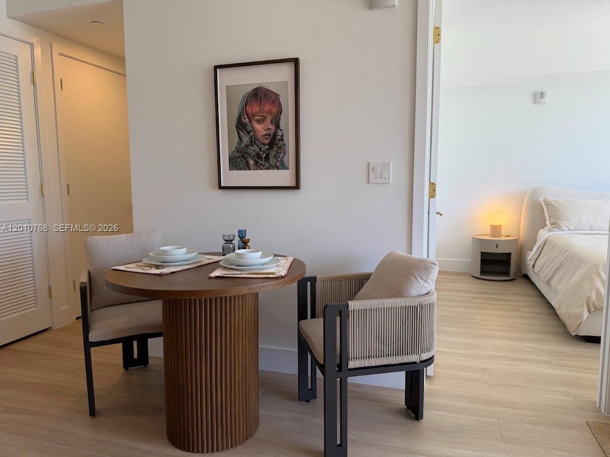 A small dining area with a round wooden table and two chairs sits near a bedroom — 90 NE 32 # 803, Miami FL 33137, MIAMI, FL