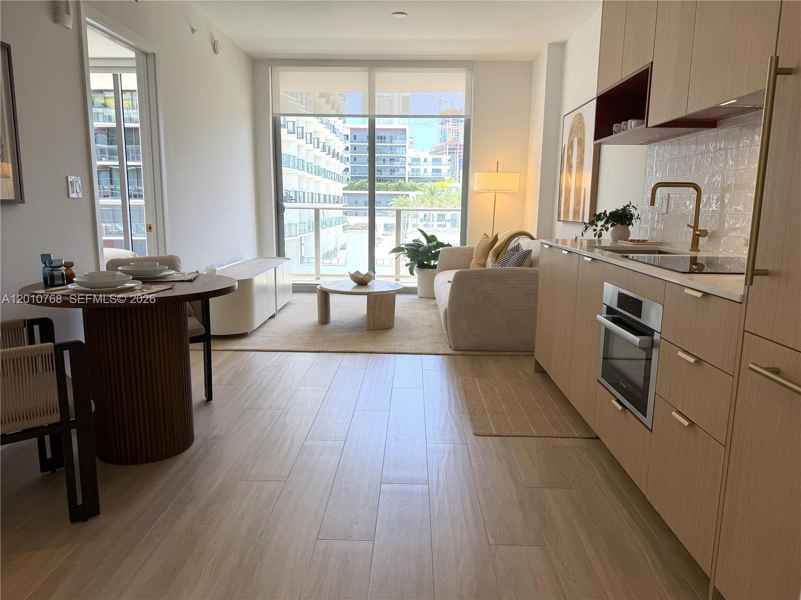 A modern studio apartment features a kitchen, dining area, and living space with balcony access — 90 NE 32 # 803, Miami FL 33137, MIAMI, FL