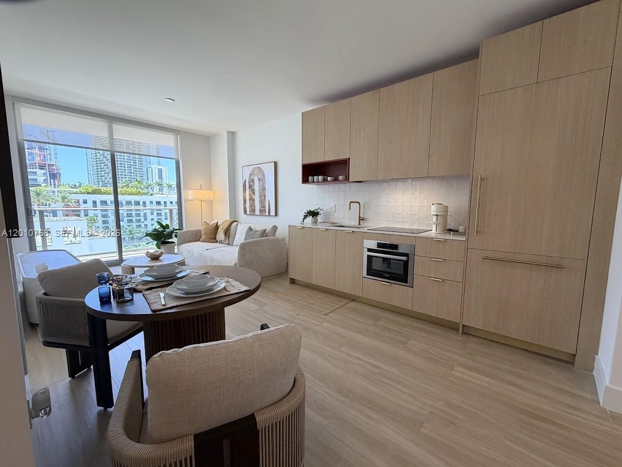 A modern studio apartment features light wood cabinetry, a small dining area, and floor-to-ceiling windows — 90 NE 32 # 803, Miami FL 33137, MIAMI, FL