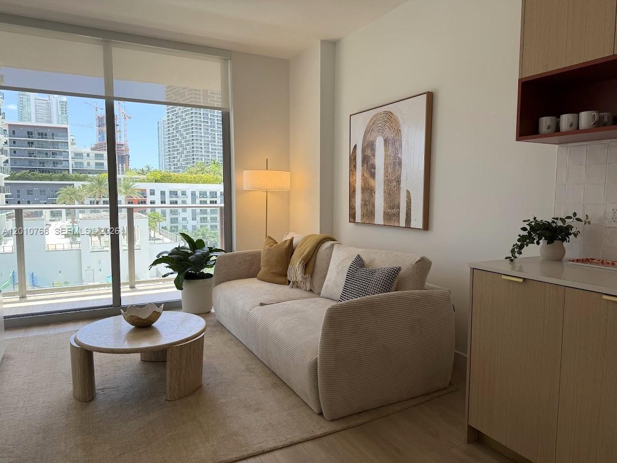 A living room features a beige sofa, round coffee table, and a balcony with city views — 90 NE 32 # 803, Miami FL 33137, MIAMI, FL