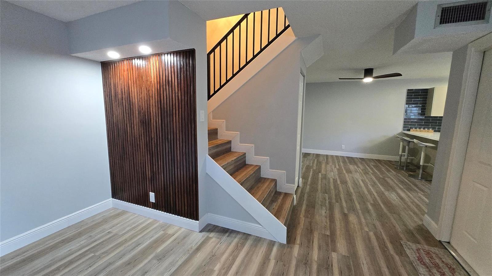 A staircase with wood treads and a slatted wood accent wall sits beside a kitchen — 8900 SW 20th Place # A, Davie FL 33324, DAVIE, FL