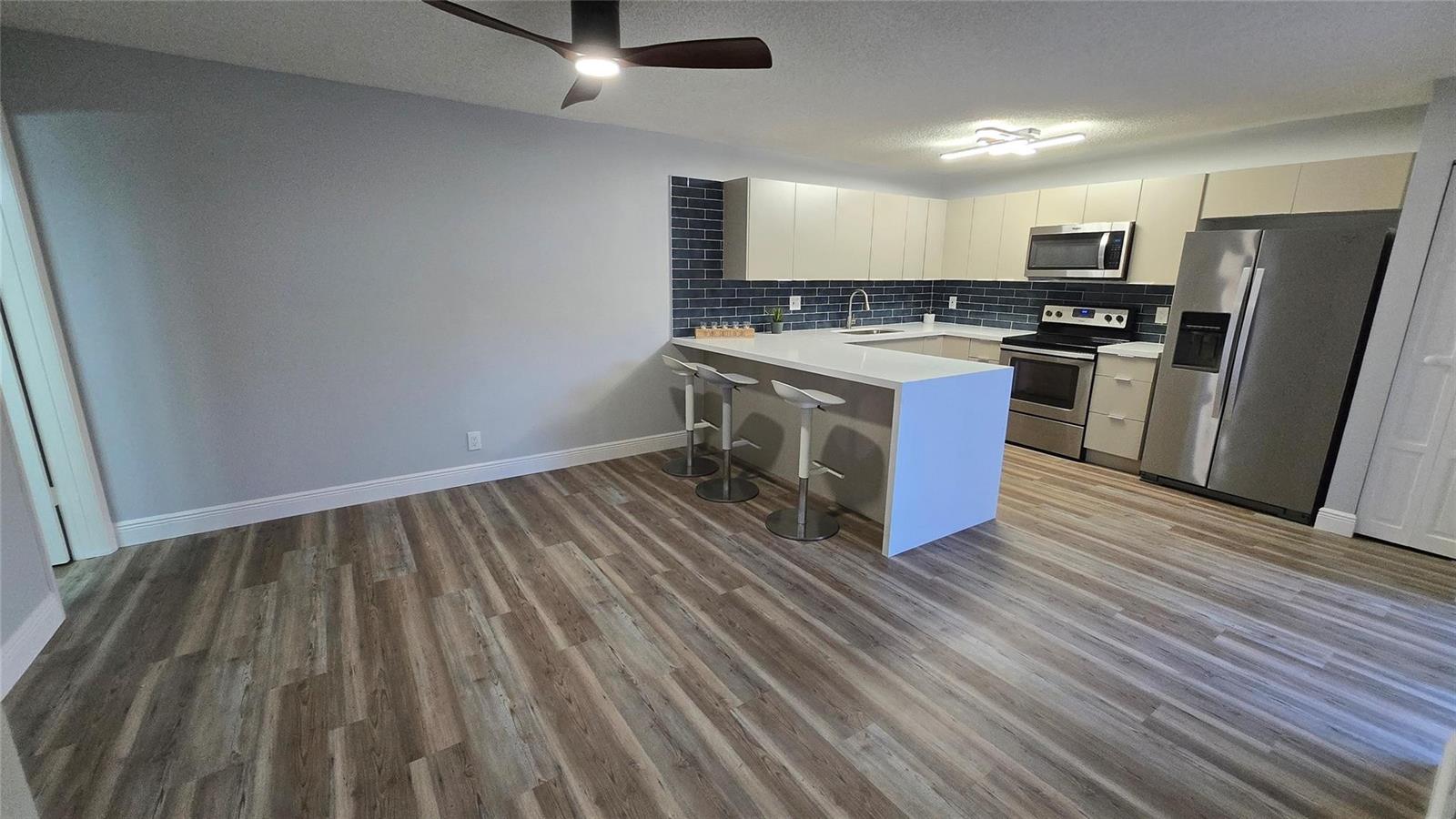A kitchen with white cabinets, a blue tiled backsplash, and a breakfast bar island — 8900 SW 20th Place # A, Davie FL 33324, DAVIE, FL