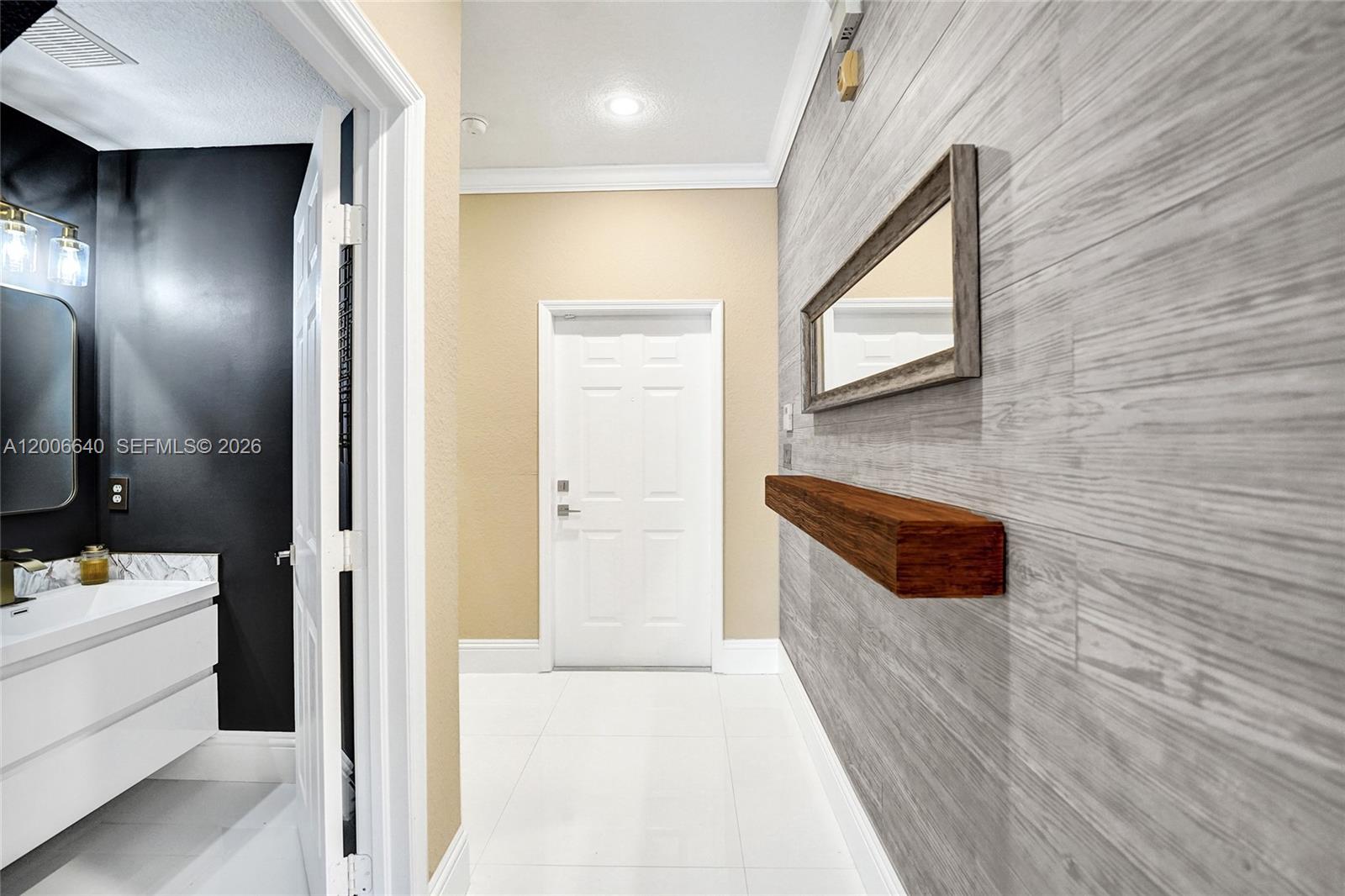 A hallway features a wood-plank accent wall, a floating shelf, a mirror, and white flooring — 5144 SW 141st Ter, Miramar FL 33027, MIRAMAR, FL
