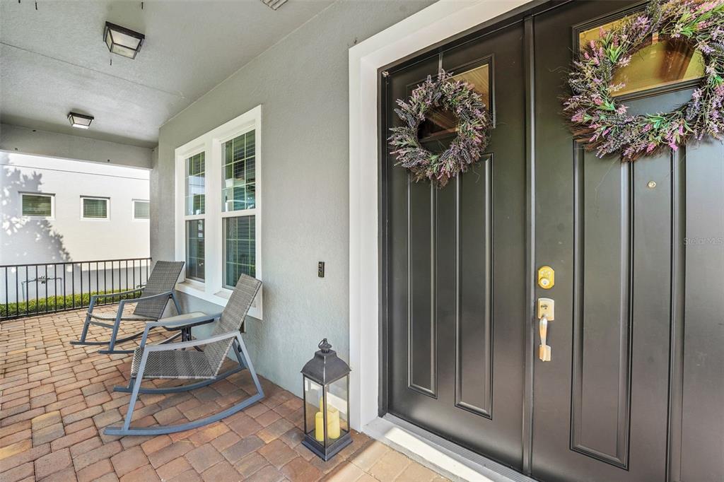 A covered porch features two rocking chairs, a lantern, and a dark double front door — 16736 GULLFLOSS TERRACE, WINTER GARDEN, FL