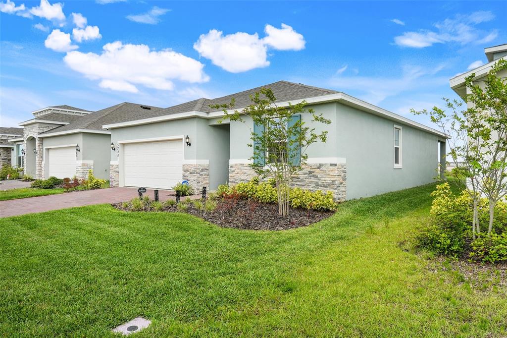 A single-story house with light green stucco, stone accents, and a two-car garage — 5724 CAMILLA STREET, ST CLOUD, FL