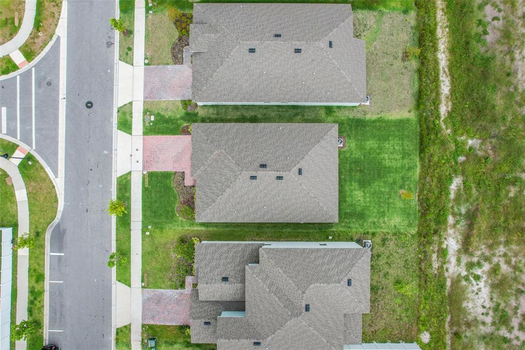 An aerial view shows three suburban houses with gray roofs and brick driveways — 5724 CAMILLA STREET, ST CLOUD, FL