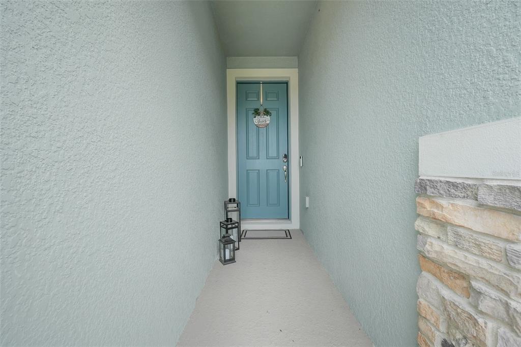 A covered entryway features a light blue front door, two lanterns, and stone siding — 5724 CAMILLA STREET, ST CLOUD, FL