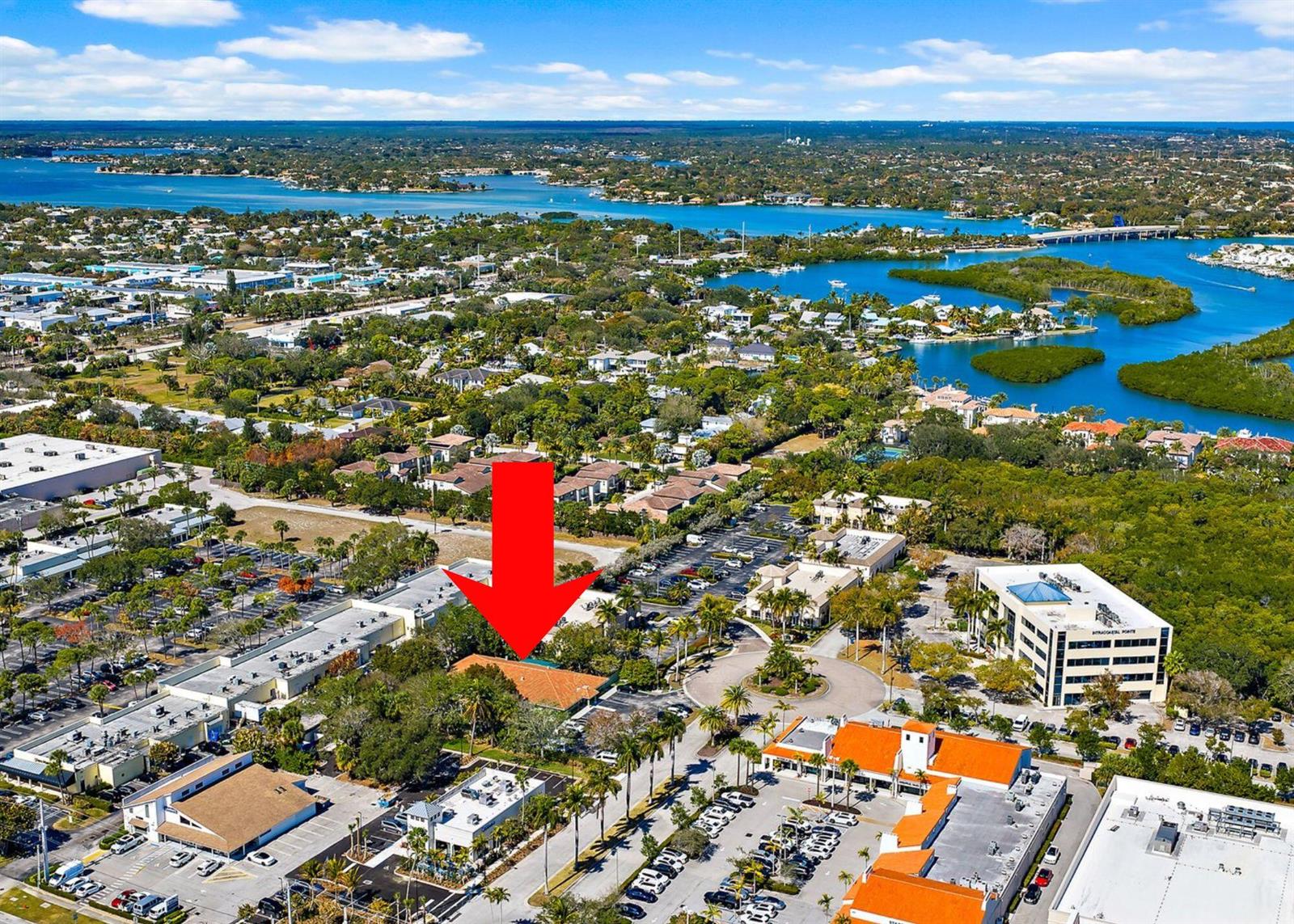 An aerial view shows a commercial building complex surrounded by parking lots and lush greenery — 100 Intracoastal Pointe Drive, Jupiter FL 33477, JUPITER, FL