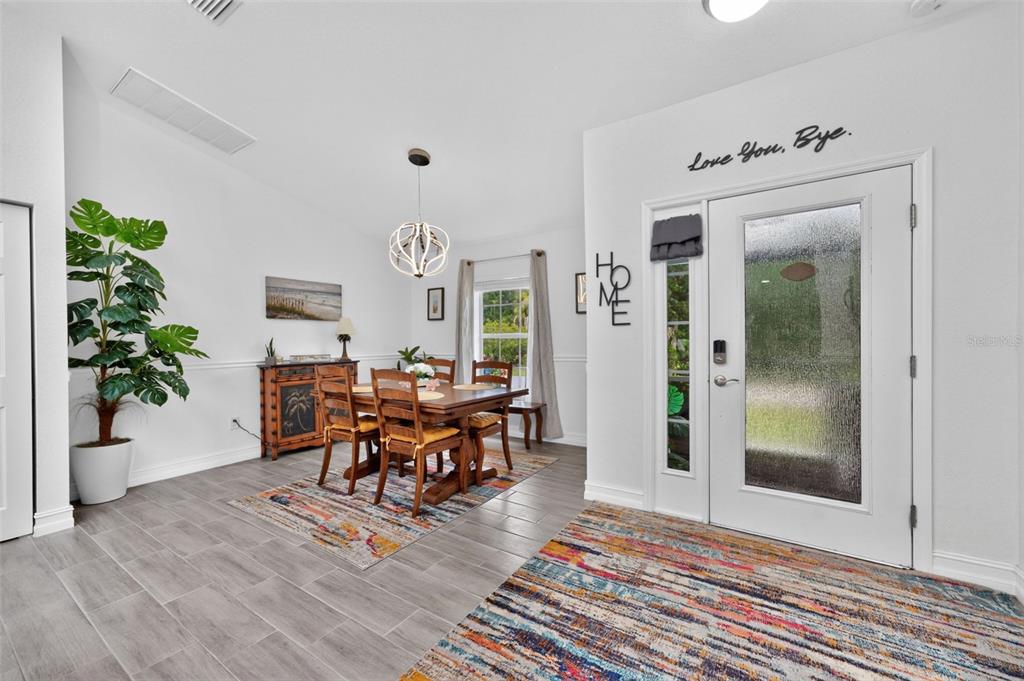 A dining area with a wooden table and chairs sits next to a front entryway — 10177 WILDCAT STREET, PORT CHARLOTTE, FL