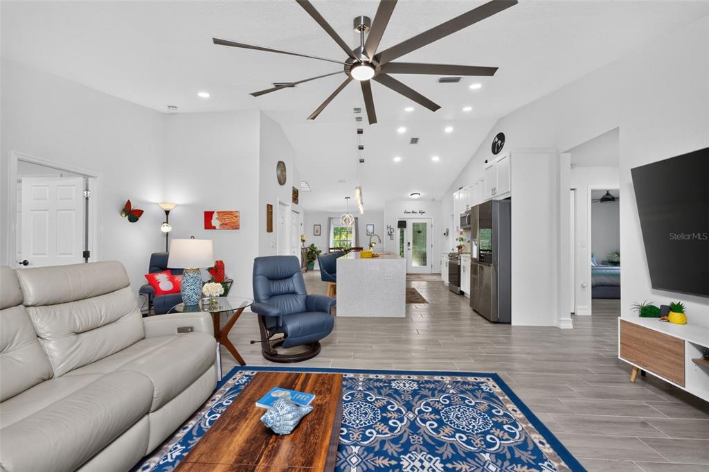An open-concept living room and kitchen feature light tile flooring, a large ceiling fan, and furniture — 10177 WILDCAT STREET, PORT CHARLOTTE, FL