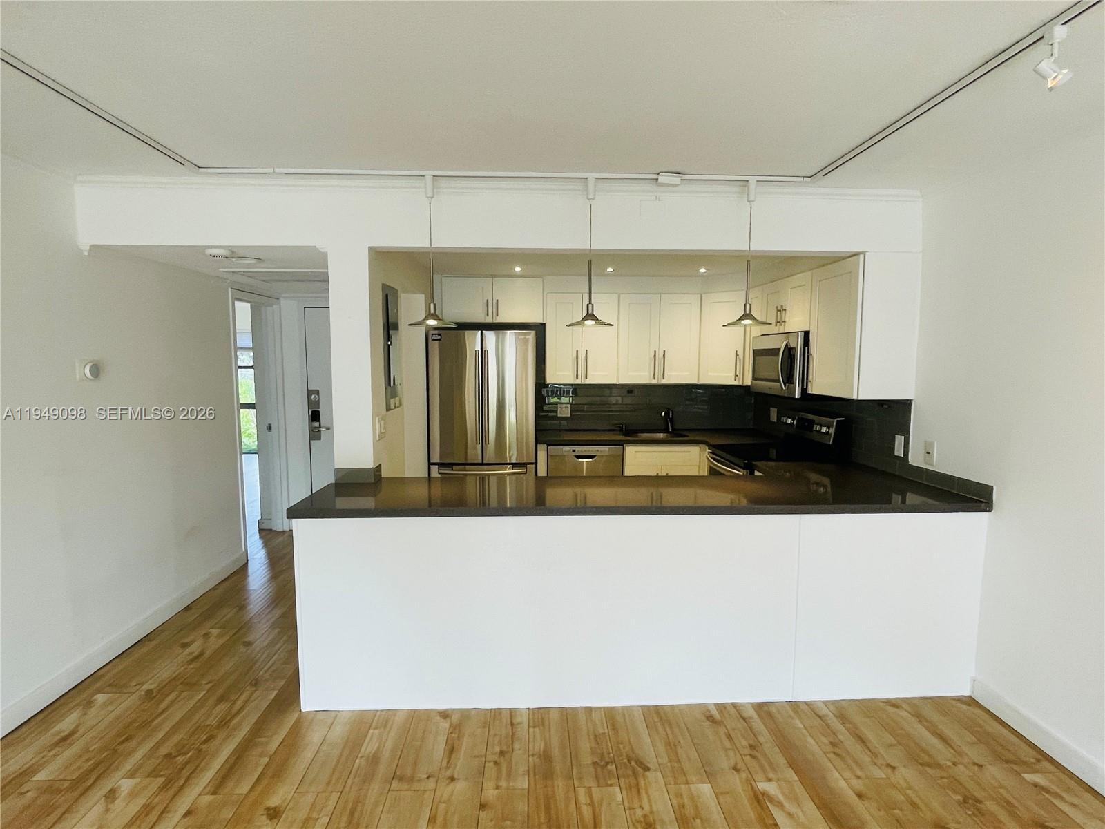 A kitchen with white cabinets, stainless steel appliances, and a dark countertop breakfast bar — 1650 NE 115th St # 311, Miami FL 33181, MIAMI, FL